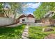 Wide shot of a backyard with lush lawn, tall fence, metal planter, and garden rock at 3024 S Sherman St, Englewood, CO 80113