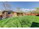 Brick home with a spacious, green backyard featuring a covered patio area and wood fencing at 6280 Quay St, Arvada, CO 80003