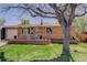 Charming brick home featuring a well-maintained lawn, brick planter, and mature tree in a quiet neighborhood at 6280 Quay St, Arvada, CO 80003