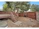 Backyard featuring a wooden deck with stairs and a stone-covered ground, enclosed by a tall, brown fence at 1972 S Carr St, Lakewood, CO 80227