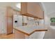 Bright kitchen featuring light wood cabinets, white appliances, and a breakfast bar overlooking a sunlit living area at 1972 S Carr St, Lakewood, CO 80227