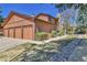 Exterior view of a well-maintained home with a three-car garage, lush landscaping, and mature trees at 9501 W 89Th Cir, Broomfield, CO 80021