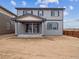 Two-story home's back exterior features gray siding, a covered patio, and a spacious, unfinished yard at 45909 Wood Thrush Ave, Bennett, CO 80102