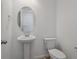 Modern powder room with pedestal sink, oval mirror, and white commode at 45909 Wood Thrush Ave, Bennett, CO 80102