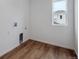 Bright laundry room with wood floors, white walls, and window at 45909 Wood Thrush Ave, Bennett, CO 80102
