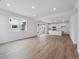Open-concept living room with wood floors flows into a kitchen with white cabinets and stainless appliances at 45909 Wood Thrush Ave, Bennett, CO 80102