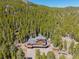 Aerial view of the log home with surrounding decks, outbuilding and driveway amid a dense forest at 3581 Gap Rd, Golden, CO 80403