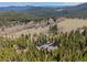 Drone view of a rustic log home surrounded by a vibrant forest and distant mountains at 3581 Gap Rd, Golden, CO 80403