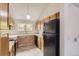 Well-lit kitchen with wooden cabinets, black refrigerator, and tile flooring at 3558 S Depew St # 302, Denver, CO 80235