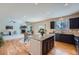 Open-concept kitchen and living space with a granite island, dark cabinets, and hardwood floors at 24288 E Brandt Ave, Aurora, CO 80016