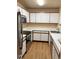 Galley kitchen with white cabinets, stainless steel appliances, and wood-look floors at 5775 W Atlantic Pl # 103, Lakewood, CO 80227