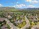 Expansive aerial view of a residential community nestled near mountains and lush greenery under a bright, cloudy sky at 16753 W 61St Ln, Golden, CO 80403