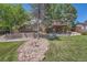 A spacious backyard featuring manicured lawn, stone garden, mature trees, and an upper deck at 11410 W 72Nd Pl, Arvada, CO 80005