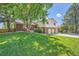 Landscaped front yard featuring a lush green lawn, mature trees, and charming two-story brick accents at 11410 W 72Nd Pl, Arvada, CO 80005