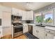 Well-equipped kitchen with stainless steel appliances, white cabinets, and a sleek countertop under natural light at 11410 W 72Nd Pl, Arvada, CO 80005