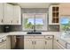 Bright kitchen boasts white cabinets, stainless steel appliances, and a window with a scenic view at 11410 W 72Nd Pl, Arvada, CO 80005