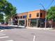 Brick buildings stand on a street corner with flower boxes, crosswalks, and street signs visible at 4057 Bryant St, Denver, CO 80211