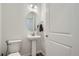 Well-lit half bathroom features pedestal sink, oval mirror, and modern fixtures at 8376 Lorenzo Ln # C, Littleton, CO 80129