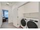 Bright laundry area with a washer, dryer, and overhead shelving, conveniently located next to a bedroom at 8376 Lorenzo Ln # C, Littleton, CO 80129