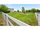 Large backyard with a white fence, lush green grass, and a view of the home at 10170 E 151St Ct, Brighton, CO 80602