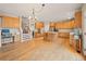 Open concept kitchen with wood cabinets, island seating, hardwood floors, and easy access to the living area at 10170 E 151St Ct, Brighton, CO 80602