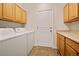 Convenient laundry room with wooden cabinets, countertop space, and modern washer and dryer at 10170 E 151St Ct, Brighton, CO 80602