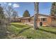 Expansive backyard with a well-manicured lawn, mature trees, and a concrete patio with a grill and dining set at 8122 W Woodard Dr, Lakewood, CO 80227