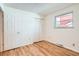 Clean, neutral bedroom with a closet, window providing ample natural light, and wood floors at 8122 W Woodard Dr, Lakewood, CO 80227