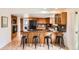 Open kitchen featuring wood cabinets, tile floors, bar seating, and modern appliances, perfect for entertaining at 8122 W Woodard Dr, Lakewood, CO 80227