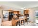 Well-lit kitchen with a center island, wood cabinetry, tile flooring, and a sliding door to the backyard at 8122 W Woodard Dr, Lakewood, CO 80227
