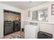 Well-lit laundry room with modern washer and dryer units, plus ample storage shelves at 772 Lewiston St, Aurora, CO 80011