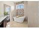 Stylish bathtub featuring mosaic tiling, luxury fixtures, and an adjacent vanity at 14025 Florence Ct, Brighton, CO 80602