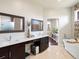 Elegant bathroom with dual sinks, a freestanding tub, and seamless access to the main bedroom at 14025 Florence Ct, Brighton, CO 80602