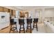 Modern kitchen with bar seating, wooden cabinets, and a view into the living space at 17423 Cornerstone Ln, Parker, CO 80134