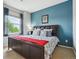 This bedroom features a queen-size bed, a blue accent wall, and a window that lets in natural light at 22932 E Ontario Dr # 102, Aurora, CO 80016