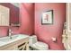 Powder room featuring a modern sink, a toilet, and textured red walls at 8807 Tuscany Ln, Highlands Ranch, CO 80130