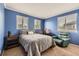 A bedroom with blue walls, a cozy armchair, a comfy bed and three windows allowing plenty of light at 8807 Tuscany Ln, Highlands Ranch, CO 80130