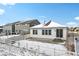 View of backyard featuring concrete patio, lawn, and white fence covered with snow at 6294 Long Branch Dr, Parker, CO 80134