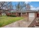 Traditional brick home with a well-maintained lawn and driveway at 6613 Independence St, Arvada, CO 80004