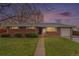 Charming brick ranch-style home with a well-manicured lawn and inviting walkway at dusk at 6613 Independence St, Arvada, CO 80004