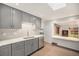 Bright kitchen with gray cabinets, tile backsplash, stainless appliances and wood flooring at 6613 Independence St, Arvada, CO 80004