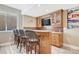 Basement bar featuring wooden cabinets, granite countertops, a mounted TV, and seating for four at 9121 Sunshine Meadow Pl, Parker, CO 80134