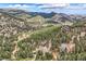 An aerial view showcases homes nestled within a vibrant green, mountainous landscape, set beneath a partly cloudy sky at 795 Pine Brook Rd, Boulder, CO 80304