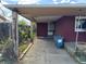 View of the carport, showing the red brick exterior, access to the back door, and weathered posts at 1985 Blackhawk St, Aurora, CO 80011