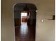 View through a unique arched hallway into the kitchen with tile flooring and aged walls at 1985 Blackhawk St, Aurora, CO 80011