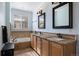 Bathroom featuring dual sinks, granite counters, light wood cabinets and a tub under a bright window at 10127 Bluffmont Ln, Lone Tree, CO 80124