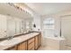 Bathroom showcasing double sinks, wood cabinets, and a separate shower and soaking tub at 20000 Mitchell Pl # 51, Denver, CO 80249