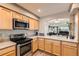 A kitchen featuring light wood cabinets, stainless steel appliances, and an opening to the living room at 20000 Mitchell Pl # 51, Denver, CO 80249