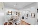 Open-concept kitchen and dining area with hardwood and tiled flooring, bright white walls, and modern finishes at 3067 S Holly Pl, Denver, CO 80222