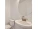 Bright half-bathroom features white pedestal sink, brushed nickel faucet, and circular mirror at 6926 Kendrick Ln, Arvada, CO 80007
